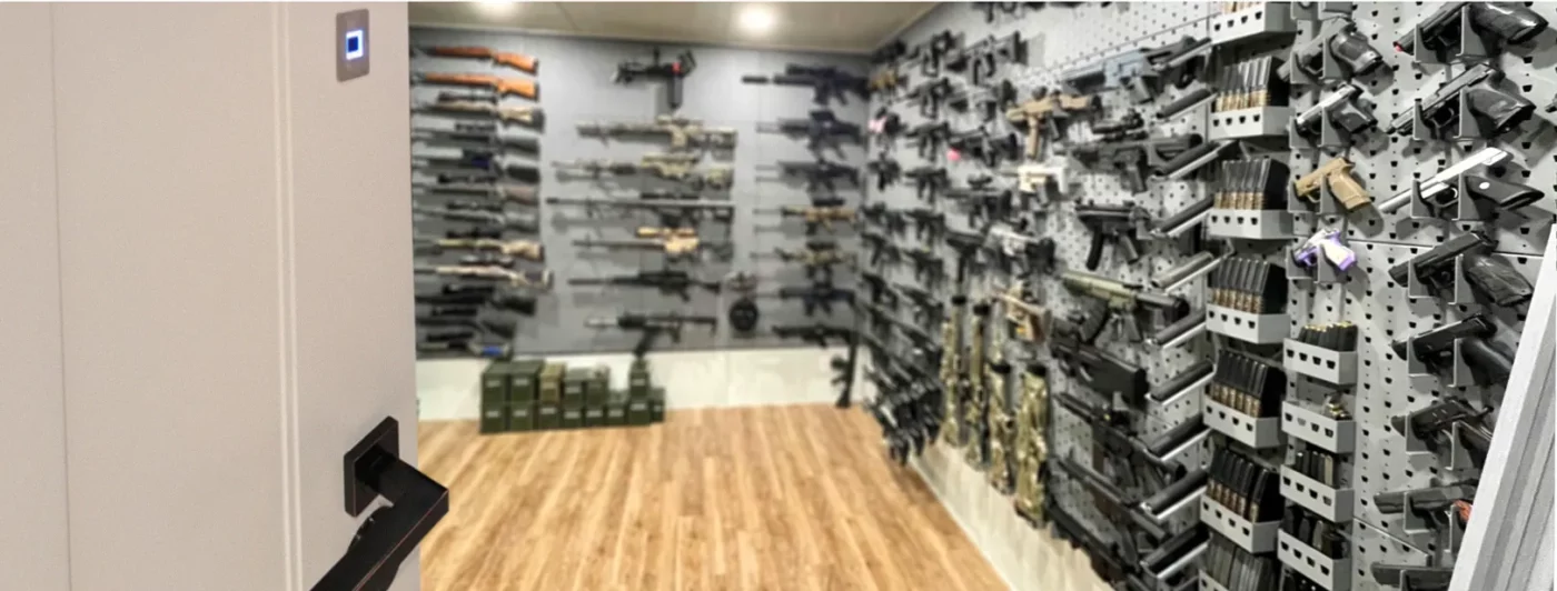 Wood biometric gun room door with large firearm collection on walls behind