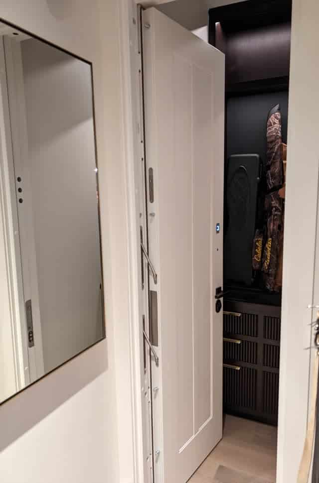 Gun room door standing open, showing the armored edge of the leaf and the cabinet inside.
