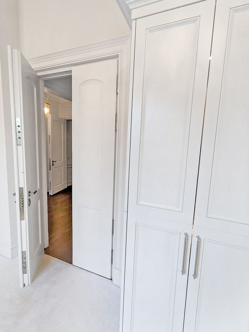 Painted white safe room door standing open beside built-in closet wardrobes.